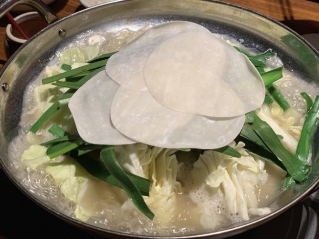 たっぷりのモツと野菜のうえに、餃子の皮でフタをして蒸し煮チックに。(この餃子の皮がビロビロしてとっても美味しい)