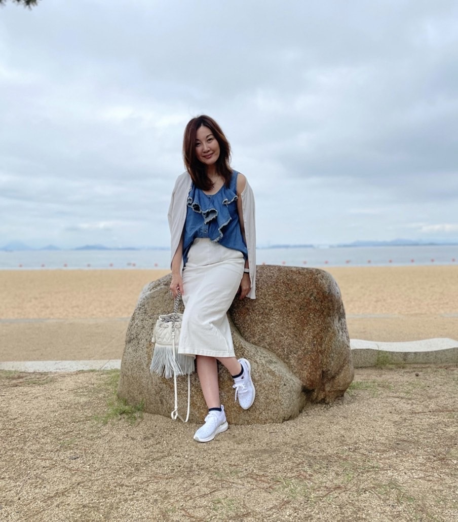 後ろ海 岩の上に座る女性