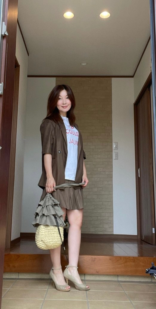 玄関女性 ブラウンの半袖ジャケットにショートパンツ
